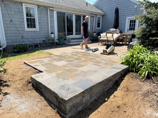 Raised Paver Patio — Plymouth, MA Raised paver patio under construction behind a home in Plymouth, MA